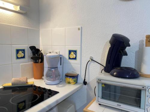 a kitchen with a microwave on top of a counter at Le Moulin Maison Internet WiFi Parking Terrasse Résidence avec Piscine in Portiragnes