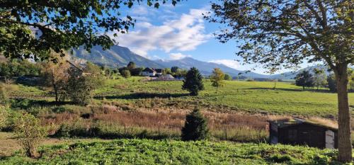 un champ avec une maison et des montagnes en arrière-plan dans l'établissement Grande maison familiale jusqu'à 14 personnes à Lans en Vercors, à Lans-en-Vercors