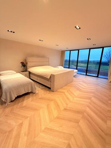 two beds in a bedroom with wood floors and windows at Luxury Apartment near Amsterdam in Purmerland