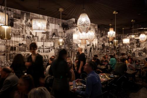 a crowd of people sitting in a restaurant with chandeliers at Hotel AMO by AMANO Friedrichstraße in Berlin