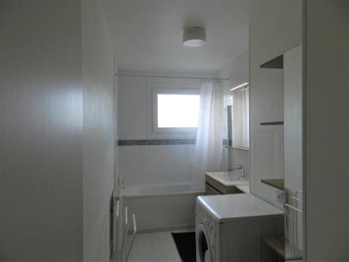 une salle de bain avec une baignoire, un lavabo et une fenêtre dans l'établissement Appartement lumineux Rennes, à Rennes