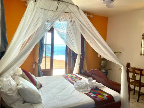 a bedroom with a canopy bed with a view of the ocean at Belle villa avec piscine à Caféière in Radelin