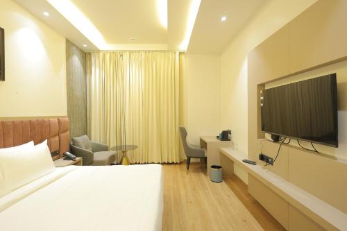 a hotel room with a bed and a flat screen tv at The Pearl Petal in Rohtak