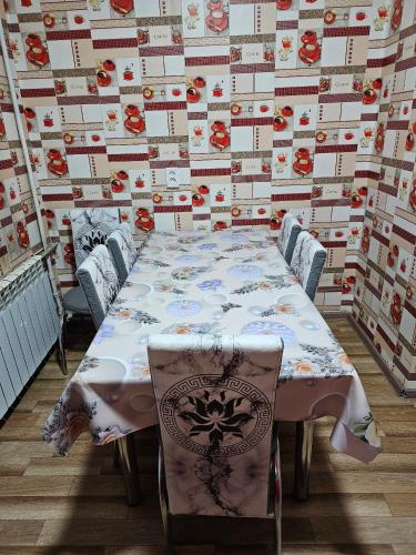 a table and chairs in a room with a wall with flowers at Guesthouse Mirlan in Karakol
