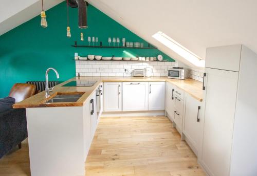 a kitchen with white cabinets and a green wall at The Loft Winchester in Winchester