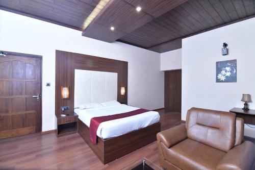 a bedroom with a bed and a couch and a chair at The Garuda Hotels in Trichūr