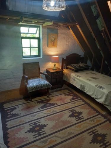 a bedroom with a bed and a chair and a window at Emerald Hill Cottage in Mount Pleasant