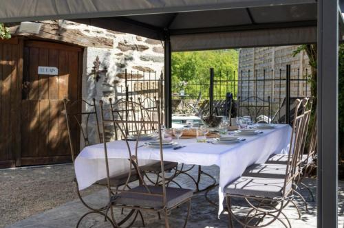 - une table blanche avec des chaises sur la terrasse dans l'établissement Newly renovated fort with panoramic landscape view jacuzzi & billiard, à Leynhac