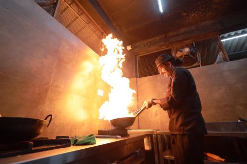 a man cooking food in a wok with flames at Kap Korome Village Resort in Koroth
