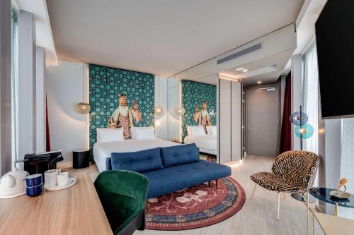 a bedroom with a king sized bed and a blue couch at nhow Amsterdam Rai in Amsterdam