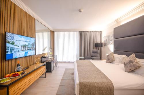 a hotel room with a bed and a flat screen tv at David Dead Sea Resort & Spa in Ein Bokek