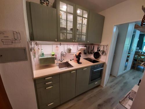 a kitchen with green cabinets and a sink at Alpenschwänchen 4 - Saalachschwänchen in Bad Reichenhall