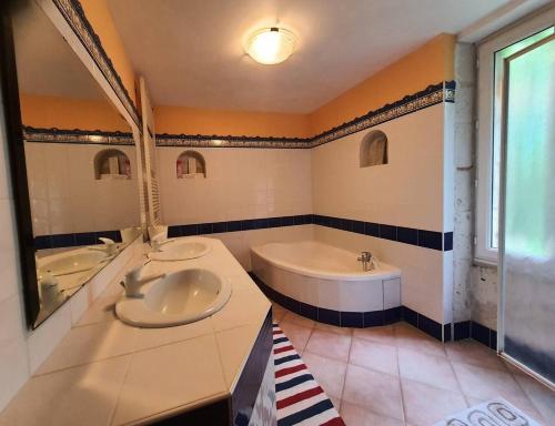 une salle de bain avec une baignoire et un lavabo et une baignoire dans l'établissement Location aux portes d'Agen - Clévacances 3 clés, à Saint-Jean-de-Thurac