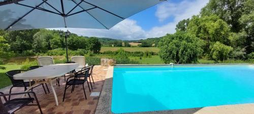 une piscine avec une table, des chaises et un parasol dans l'établissement Location aux portes d'Agen - Clévacances 3 clés, à Saint-Jean-de-Thurac