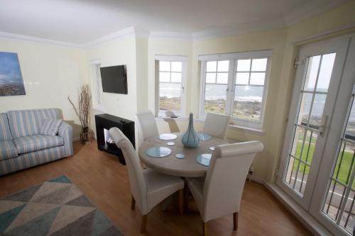 a dining room with a table with white chairs and windows at Wood Court, Troon in Troon