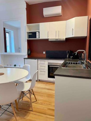 une cuisine avec des armoires blanches et une table et des chaises dans l'établissement L'Authentic, Appartement Hypercenter 4-6 personnes, à Villefranche-sur-Saône
