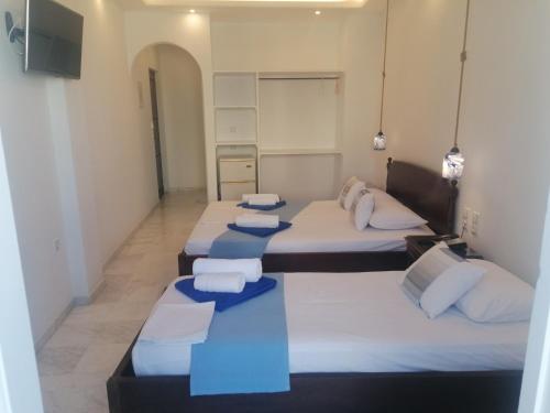 a group of four beds in a room at Adonis Hotel Naxos in Apollon