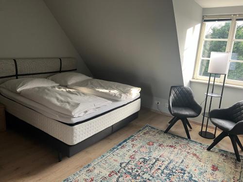 a bedroom with a bed and two chairs and a rug at Weinhaus Wöhler in Schwerin
