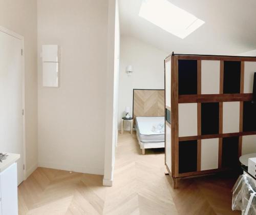 Cette chambre blanche comprend un lit et un miroir. dans l'établissement Studio 2 new over-equipped Colombes, à Colombes