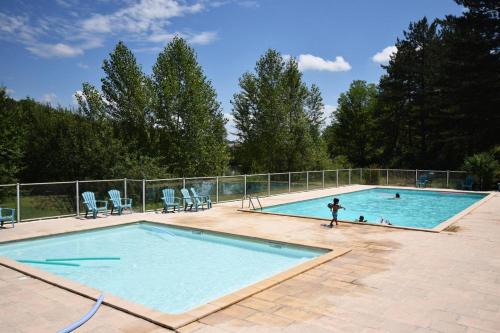 une personne joue dans une piscine dans l'établissement Petit chalet au Lac de Goulens avec piscine commune - 2 adultes et 1 enfant, à Layrac