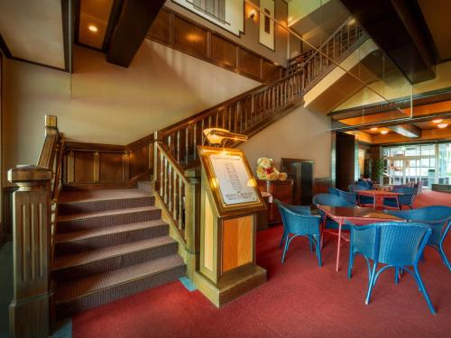 a staircase in a restaurant with blue chairs and tables at Wellness Forest Nasu in Nasu