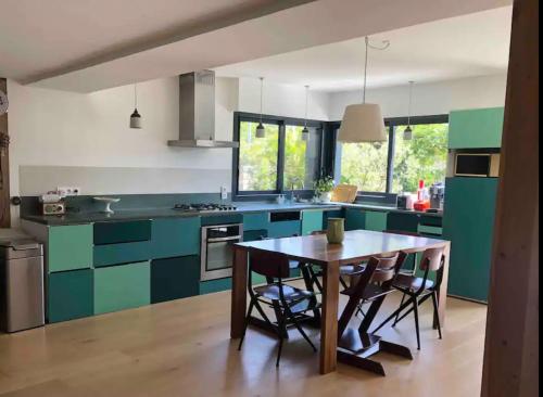 a kitchen with green cabinets and a table with chairs at Belle maison entre les sentiers côtiers et la vieille ville in Vannes