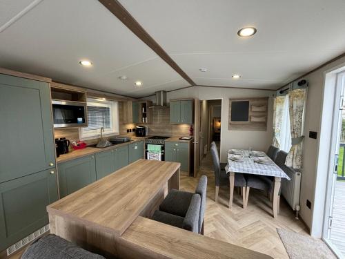 a kitchen and dining room with a wooden table at The Retreat 6 - Hot tub Mini Lodge, WiFi, pet friendly, bed linen - Golden Palm Resort - Meadow Lakes Caravan & Lodge Hire in Chapel Saint Leonards
