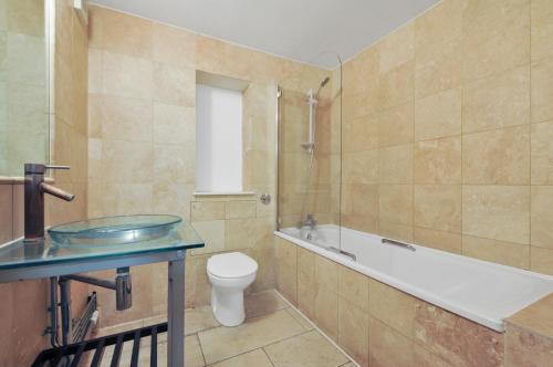 a bathroom with a tub and a toilet and a sink at Access Apartments City in London