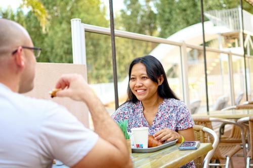 a woman sitting at a table with a man eating food at Résidence Les Castors in Calvi