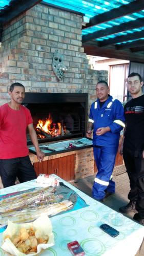 a group of men standing in front of a brick oven at Old Oak Guest House in Bellville