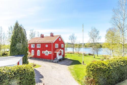 a red house with a driveway next to a lake at Central Lakefront Retreat in Hagfors