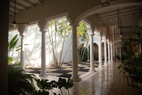 an empty porch with white columns and plants at DECU DOWNTOWN in Mérida