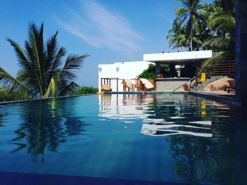 a swimming pool with blue water in front of a house at Rumassala Villas in Unawatuna