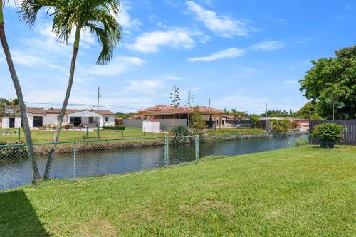 a body of water with a fence and palm trees at Casa Cabos - Fun in Miami - Pool BBQ - Fit 10 in Tamiami