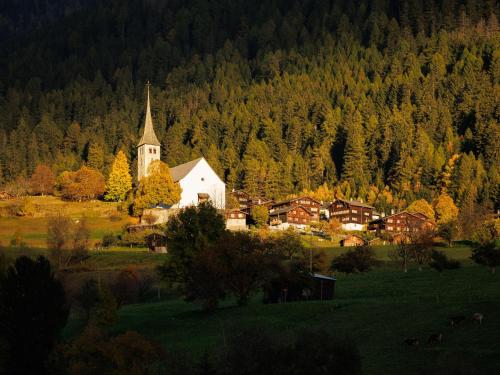 a church in the middle of a field with trees at Apartment Aragon M86 by Interhome in Fiesch