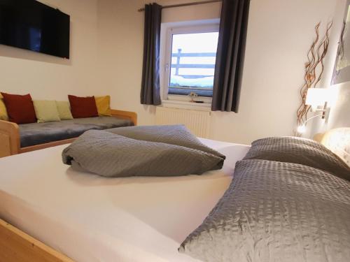 a bedroom with a bed and a couch and a window at Apartment Piz Mundin by Interhome in Spiss