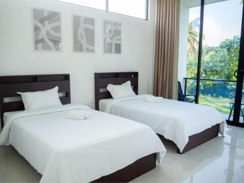 two beds in a hotel room with white sheets at Mates Villa in Weligama