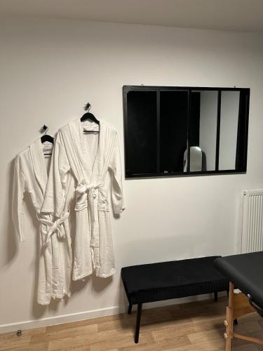 two white robes hanging on a wall next to a window at Lescapade Paris spa in Vauréal