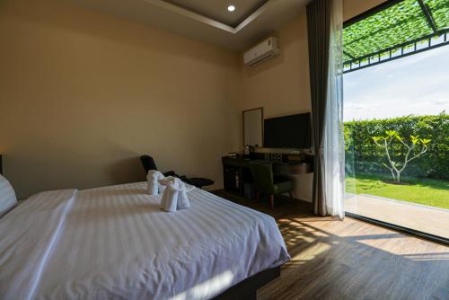 a bedroom with a bed and a desk and a window at Momtikcamp Hotel in Ban Nong Muang