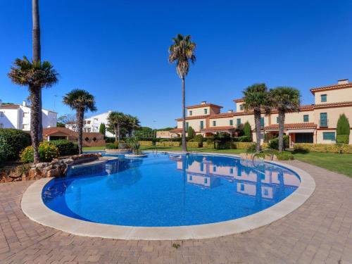 a large swimming pool with palm trees and buildings at Apartment Port Pals Golden by Interhome in Pals
