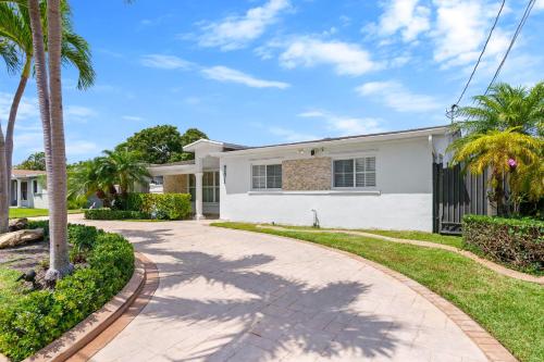 a white house with palm trees and a driveway at Casa Cabos - Fun in Miami - Pool BBQ - Fit 10 in Tamiami