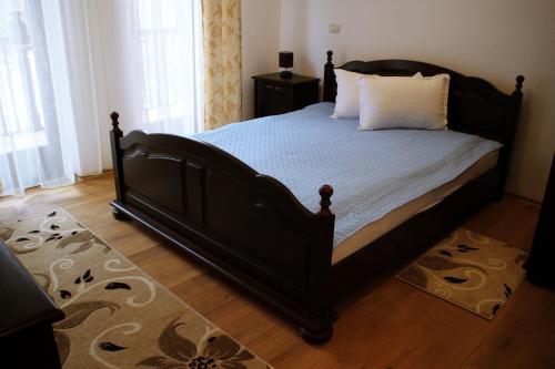 a bedroom with a bed with a black frame and white sheets at Pensiunea Crimar in Ilteu