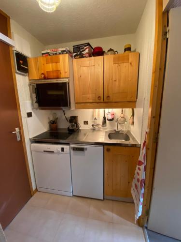 Elle comprend une petite cuisine avec des placards en bois et un évier. dans l'établissement Chez mon Grand-père, à Valmorel