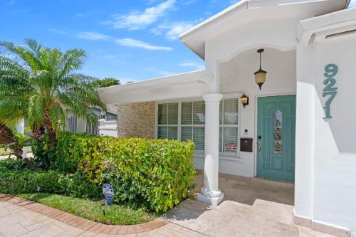 a white house with a green door and a palm tree at Casa Cabos - Fun in Miami - Pool BBQ - Fit 10 in Tamiami