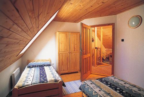 a room with two beds and a wooden ceiling at Horská chata Stará Horáreň 1 in Dobšiná