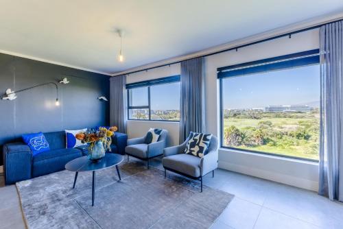 a living room with blue furniture and a large window at Waters Edge Apartments in Cape Town