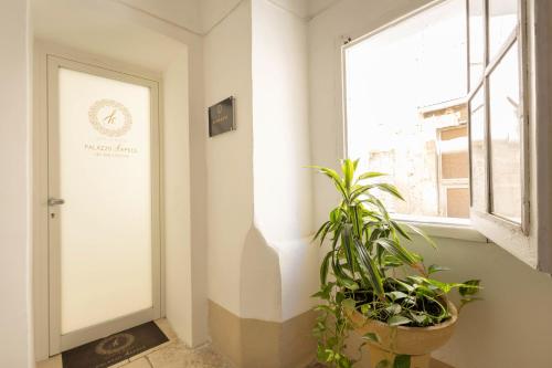a hallway with a door and a plant next to a window at Palazzo Kapece in Monopoli