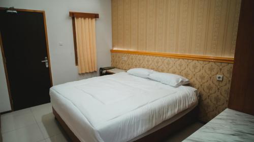 a hotel room with a white bed and a window at The Canal Homestay in Probolinggo