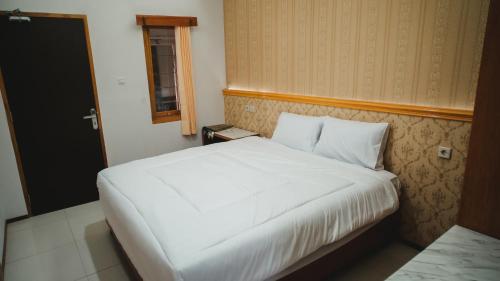 a white bed in a room with a window at The Canal Homestay in Probolinggo