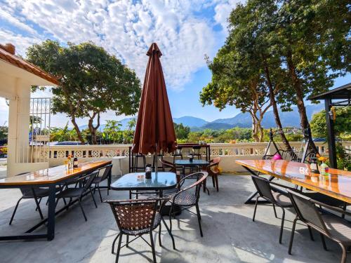 a patio with tables and chairs and an umbrella at Cloud Tree Inn Boutique Guesthouse XiChong DaPeng ShenZhen 深圳大鹏西涌云树里民宿Yun Shu Li in Shenzhen